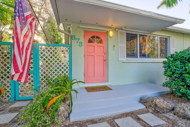 doorway to property featuring fence and stucco siding