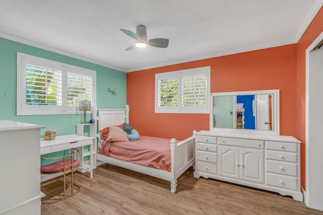 bedroom featuring light wood-style flooring, multiple windows, a ceiling fan, and crown molding