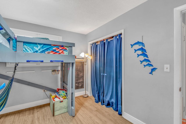 bedroom featuring a textured ceiling, wood finished floors, and baseboards