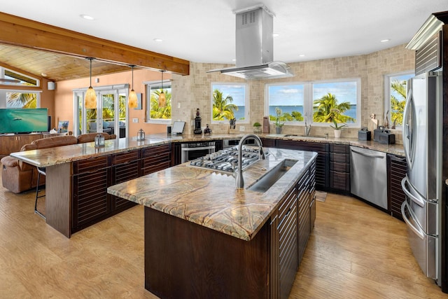 kitchen featuring stainless steel appliances, light stone countertops, a kitchen island, and island range hood