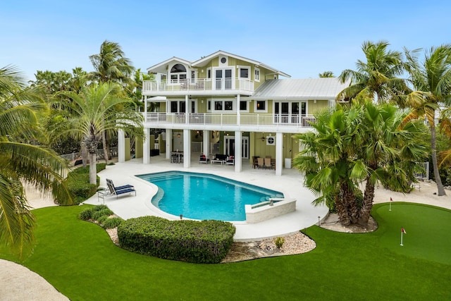 rear view of property with a patio, a balcony, and a yard