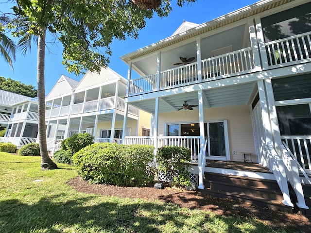 rear view of house with ceiling fan, a yard, and a balcony