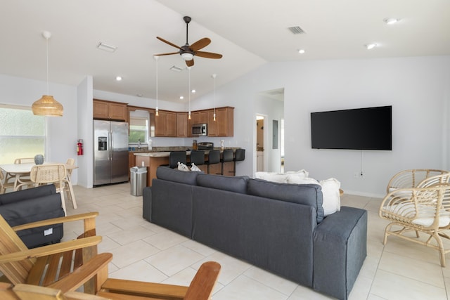 living room featuring ceiling fan, vaulted ceiling, and light tile patterned floors