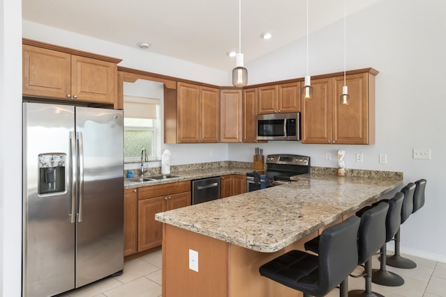 kitchen with sink, appliances with stainless steel finishes, a kitchen breakfast bar, decorative light fixtures, and kitchen peninsula