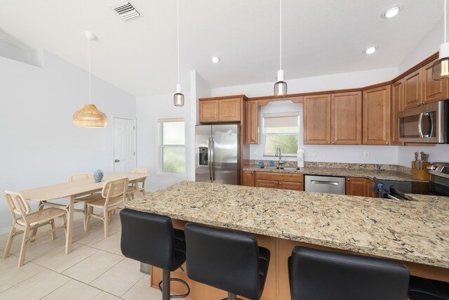 kitchen featuring vaulted ceiling, sink, hanging light fixtures, light stone counters, and stainless steel appliances