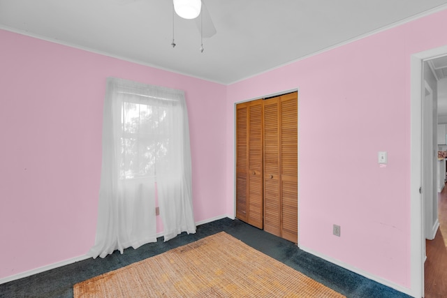 unfurnished bedroom featuring dark carpet, a closet, and ceiling fan