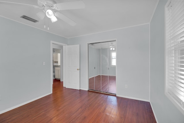 unfurnished bedroom with a closet, crown molding, dark hardwood / wood-style floors, and ceiling fan