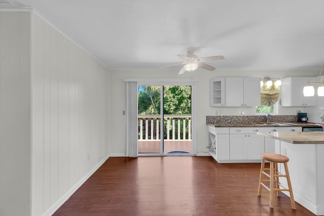 kitchen featuring ceiling fan, dark hardwood / wood-style floors, white cabinets, and a kitchen bar