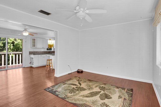 spare room featuring wood-type flooring, ceiling fan, and crown molding