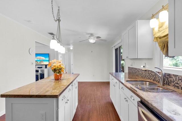 kitchen featuring sink, decorative light fixtures, stainless steel dishwasher, a kitchen island, and white cabinets