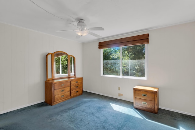 unfurnished bedroom with ceiling fan, ornamental molding, and dark carpet