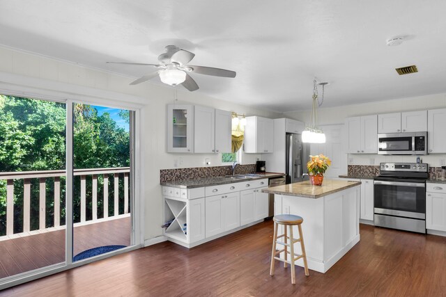 kitchen with sink, a kitchen island, white cabinets, and appliances with stainless steel finishes