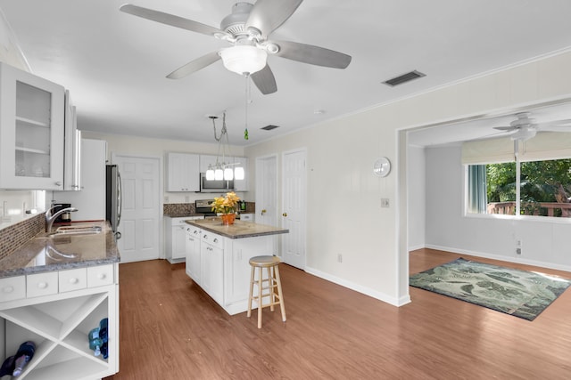 kitchen featuring sink, hanging light fixtures, appliances with stainless steel finishes, a kitchen island, and white cabinets