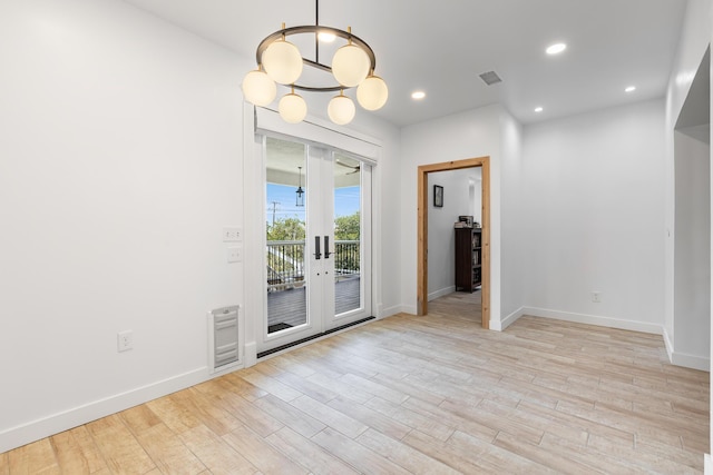 spare room featuring french doors, a notable chandelier, and light hardwood / wood-style flooring