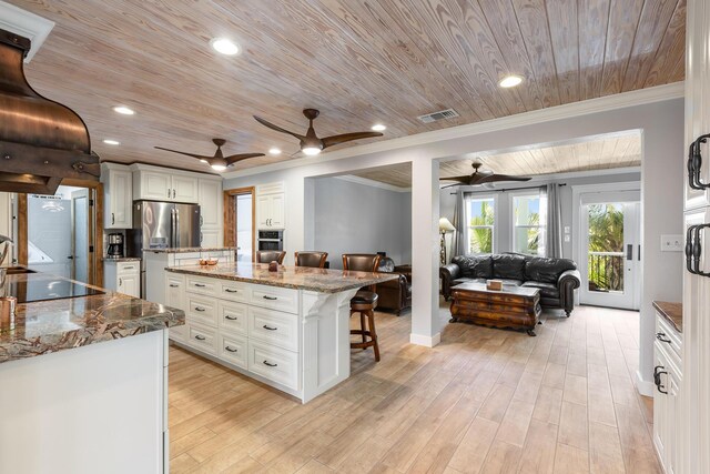 kitchen featuring a kitchen bar, stainless steel appliances, a center island, white cabinets, and stone countertops