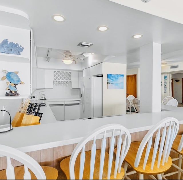 kitchen featuring white cabinetry, white fridge with ice dispenser, sink, and kitchen peninsula