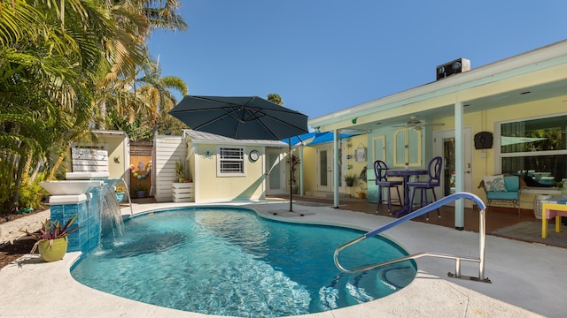 view of pool with a patio area, pool water feature, ceiling fan, and a storage unit