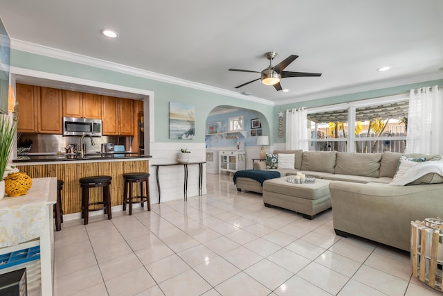 living room featuring sink, ornamental molding, ceiling fan, and light tile patterned flooring