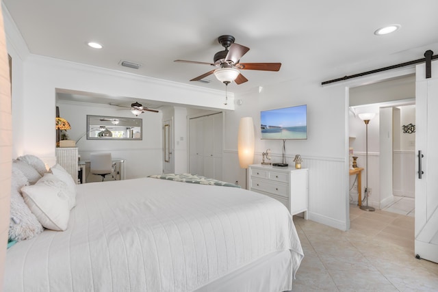 tiled bedroom featuring ceiling fan, ornamental molding, a barn door, and connected bathroom