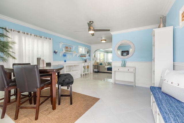 tiled dining area with ornamental molding and ceiling fan