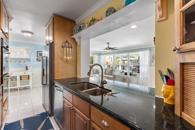 kitchen with sink, crown molding, light tile patterned floors, appliances with stainless steel finishes, and dark stone counters