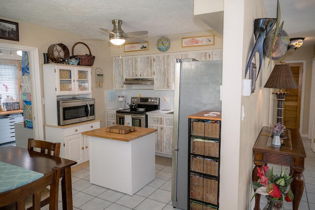 768 Musa Dr, Key Largo, FL 33037 - kitchen with appliances with stainless steel finishes, under cabinet range hood, light tile patterned floors, a ceiling fan, and wood counters