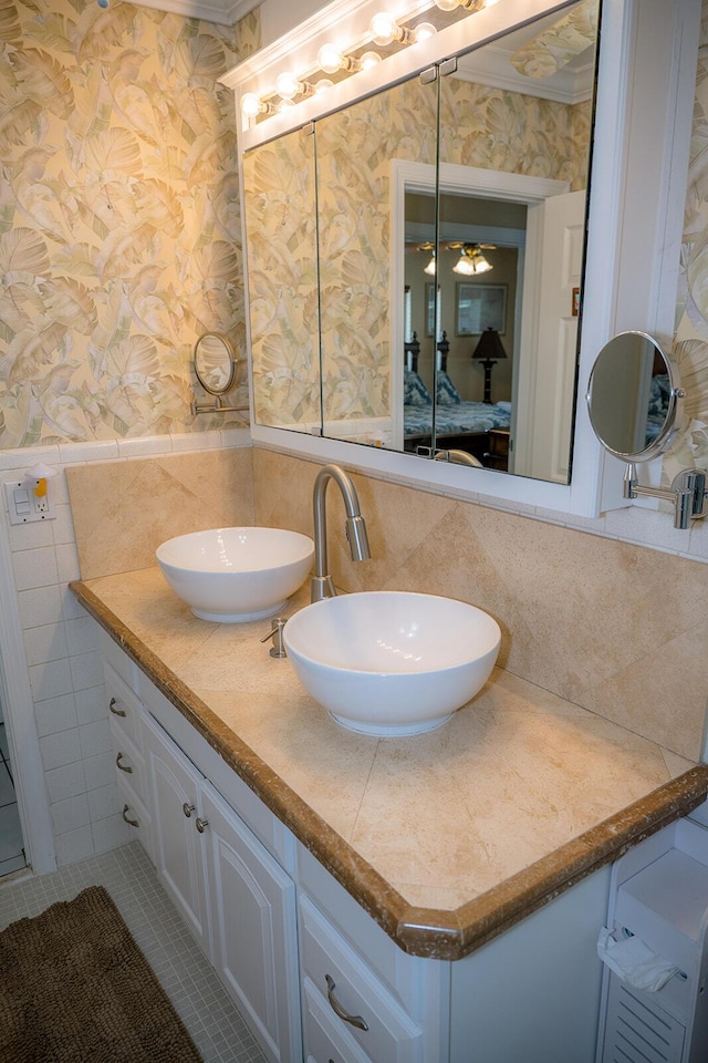 768 Musa Dr, Key Largo, FL 33037 - ensuite bathroom featuring wallpapered walls, double vanity, ornamental molding, tile walls, and tile patterned floors