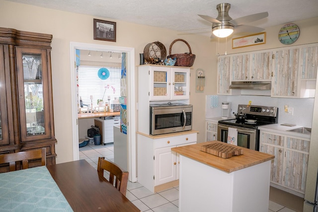 768 Musa Dr, Key Largo, FL 33037 - kitchen featuring stainless steel appliances, under cabinet range hood, light tile patterned flooring, wood counters, and a ceiling fan