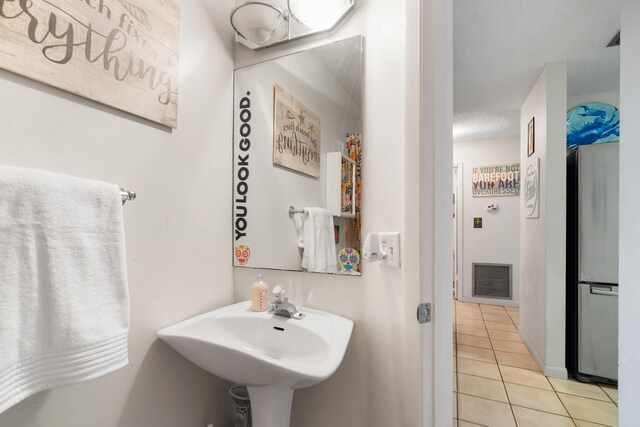 bathroom featuring tile patterned flooring, visible vents, a sink, and a textured ceiling