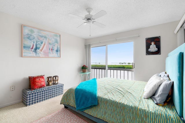 carpeted bedroom with ceiling fan, a water view, access to exterior, and a textured ceiling