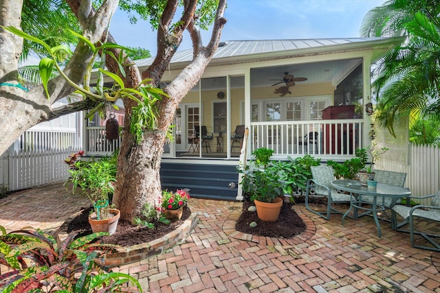 rear view of property featuring metal roof, a patio, fence, a sunroom, and a ceiling fan