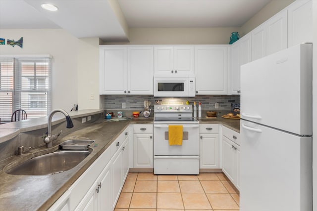 kitchen featuring white appliances, tasteful backsplash, white cabinets, dark countertops, and a sink