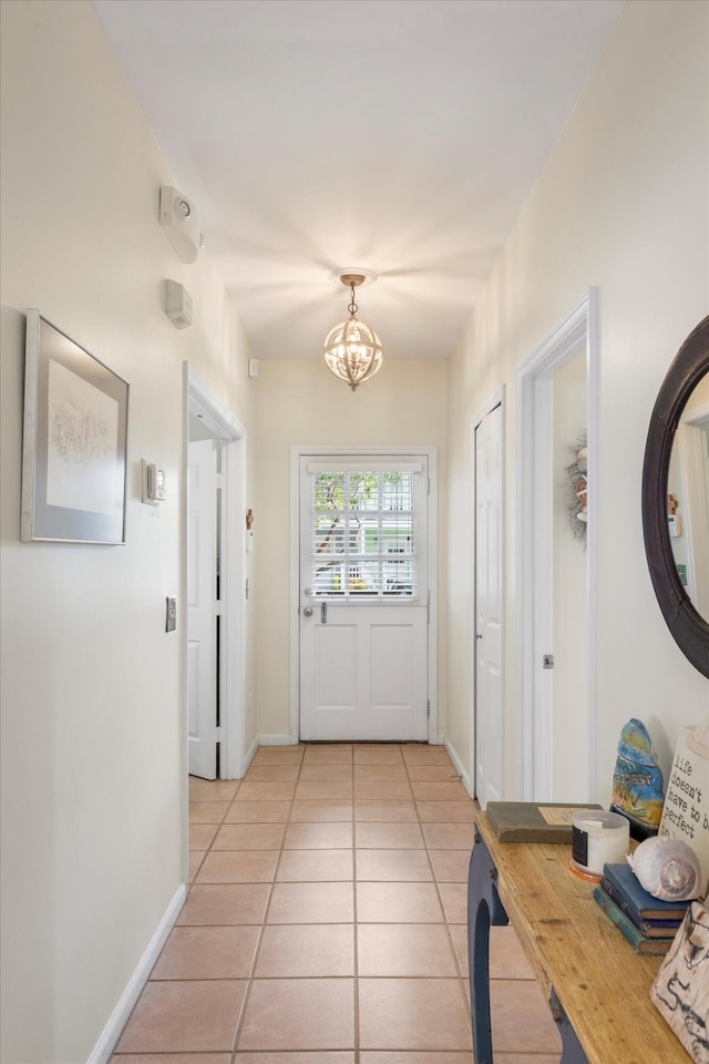 entryway with light tile patterned floors, baseboards, and a notable chandelier