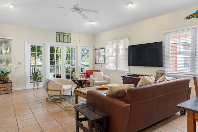 living area with light tile patterned floors, ceiling fan, baseboards, and vaulted ceiling