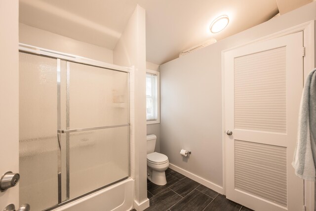 bathroom featuring bath / shower combo with glass door and toilet