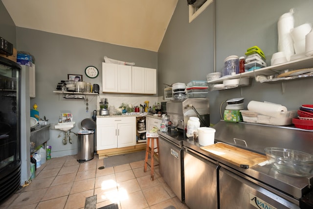 kitchen with white cabinetry, vaulted ceiling, butcher block counters, and light tile patterned floors