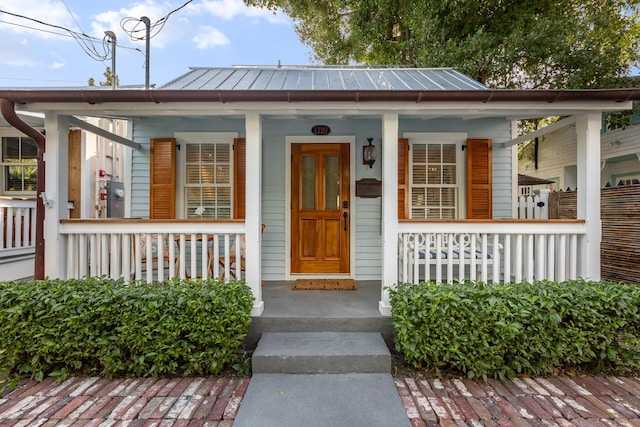 entrance to property with a standing seam roof and a porch