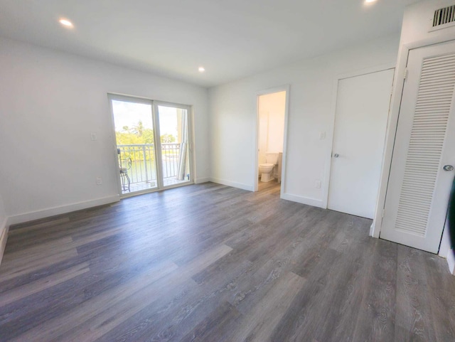 unfurnished bedroom featuring connected bathroom, access to exterior, and dark hardwood / wood-style flooring