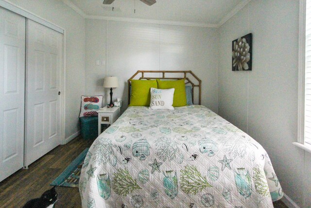 bedroom with a closet, ornamental molding, dark wood-type flooring, a ceiling fan, and baseboards