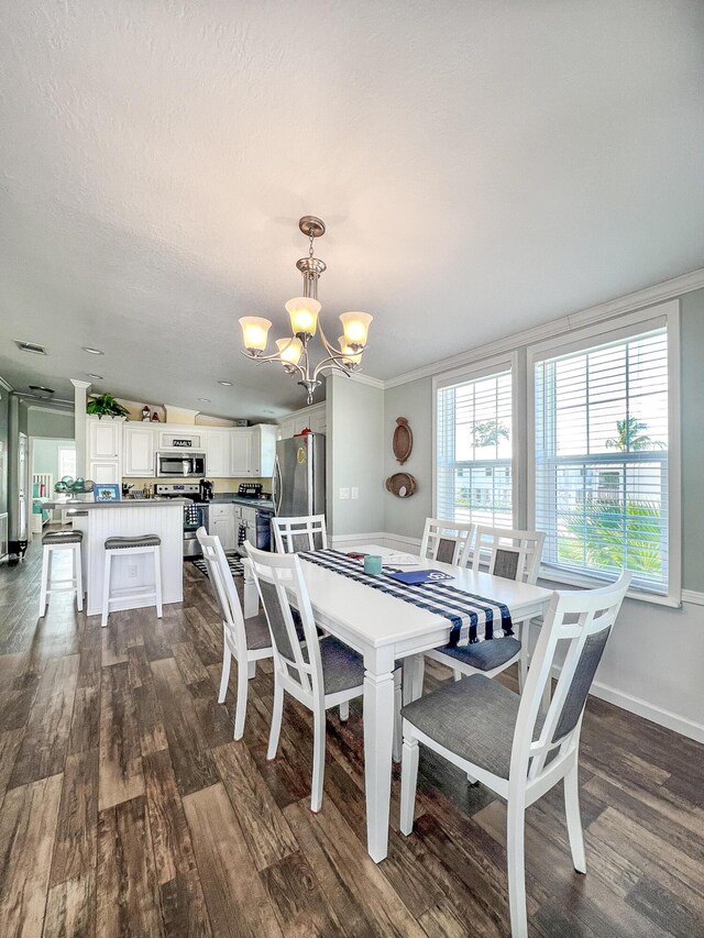 dining area with dark wood-style floors, a notable chandelier, ornamental molding, a textured ceiling, and baseboards