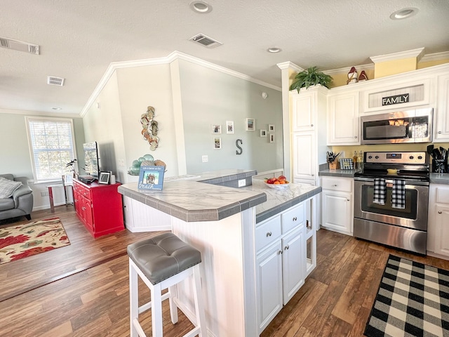 kitchen featuring a breakfast bar, visible vents, white cabinetry, and stainless steel appliances