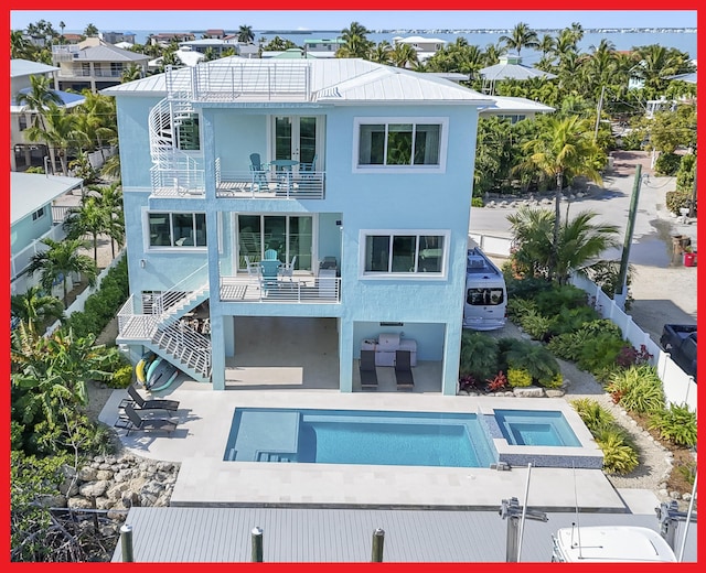 rear view of property with a balcony, a swimming pool with hot tub, and a patio area