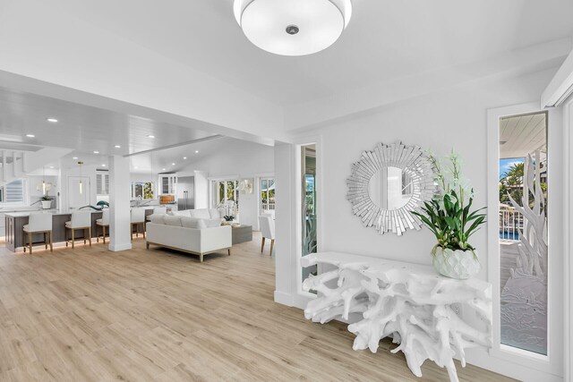 kitchen featuring sink, white cabinets, hanging light fixtures, light stone countertops, and a spacious island