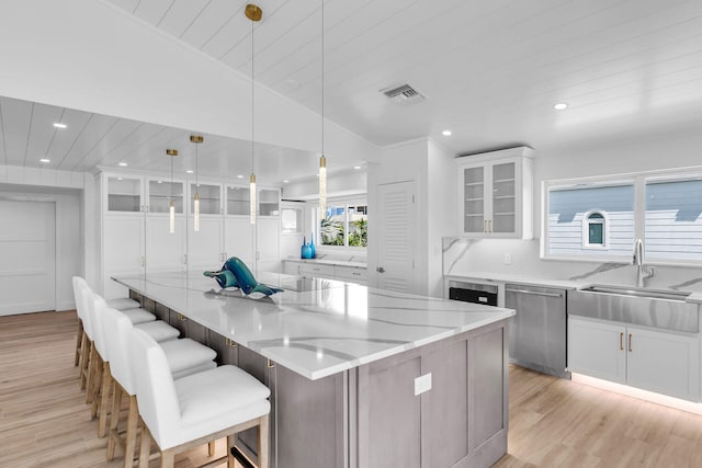 kitchen featuring a sink, white cabinetry, visible vents, light wood-style floors, and stainless steel dishwasher