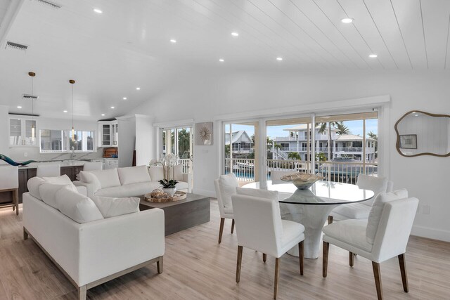 living room with lofted ceiling, sink, and light hardwood / wood-style floors