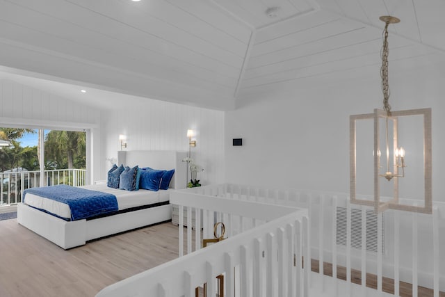 bedroom with hardwood / wood-style flooring, access to exterior, vaulted ceiling, and a notable chandelier