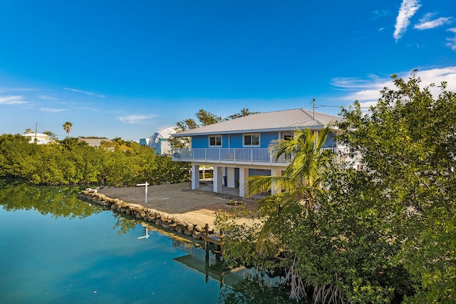 back of house featuring a water view, a balcony, and a patio