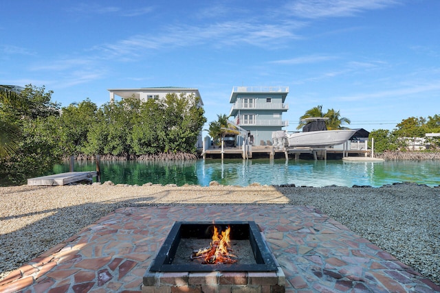 exterior space with a water view, a dock, and a fire pit