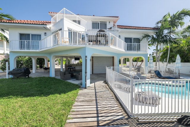 rear view of house with a fenced in pool, a patio area, and a lawn