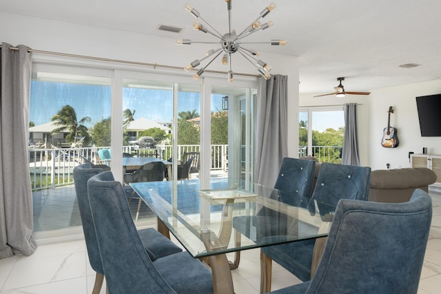 dining area with a water view, ceiling fan with notable chandelier, and a textured ceiling